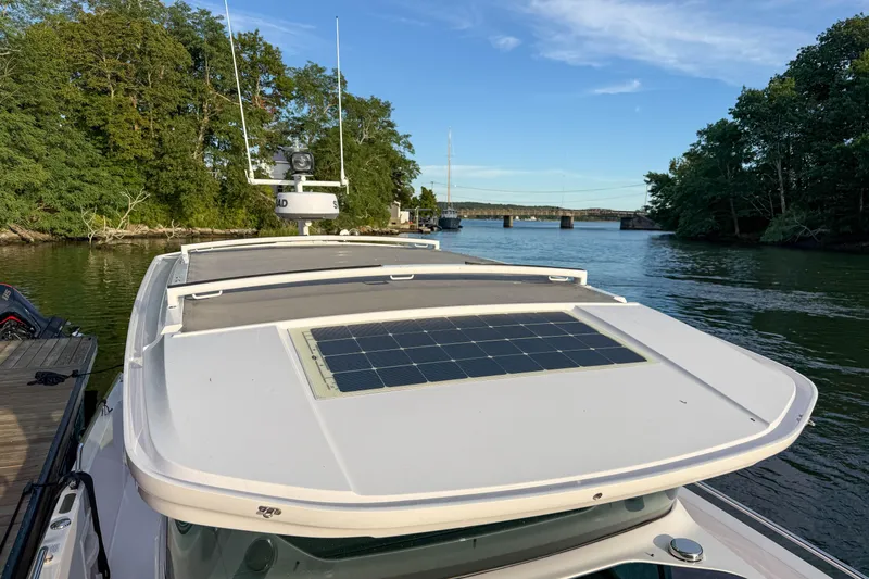 Raven Yacht Photos Pics 2021 Axopar 37 XC CROSS CABIN boat with solar panel, docked by a scenic river.