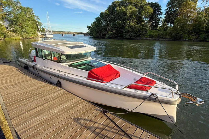 Raven Yacht Photos Pics 2021 Axopar 37 XC CROSS CABIN docked on a serene river with lush greenery.