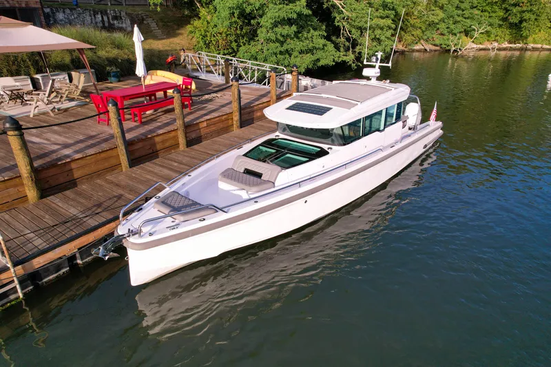 Raven Yacht Photos Pics 2021 Axopar 37 XC CROSS CABIN docked by a wooden pier, surrounded by greenery.