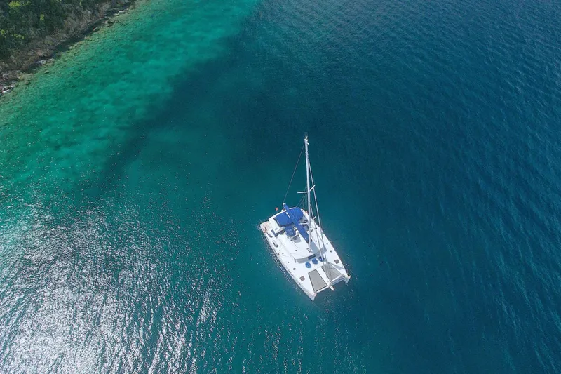 Neverland Yacht Photos Pics Aerial view of 2018 Fountaine Pajot Catamaran 67 sailing in clear blue waters.