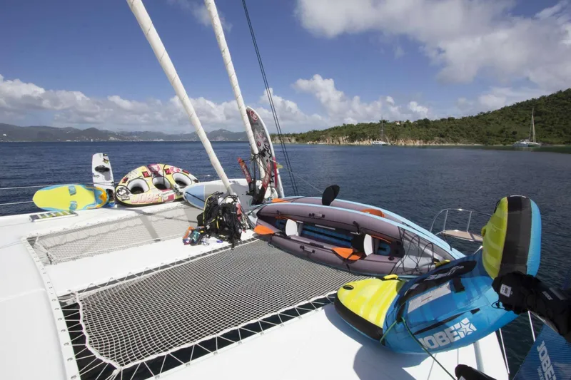 Neverland Yacht Photos Pics 2018 Fountaine Pajot Catamaran 67 with water sports gear on deck, scenic coastal view.