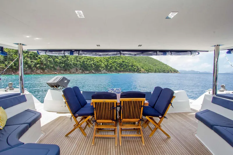 Neverland Yacht Photos Pics Luxurious 2018 Fountaine Pajot Catamaran 67 with elegant seating, overlooking serene ocean and lush island.