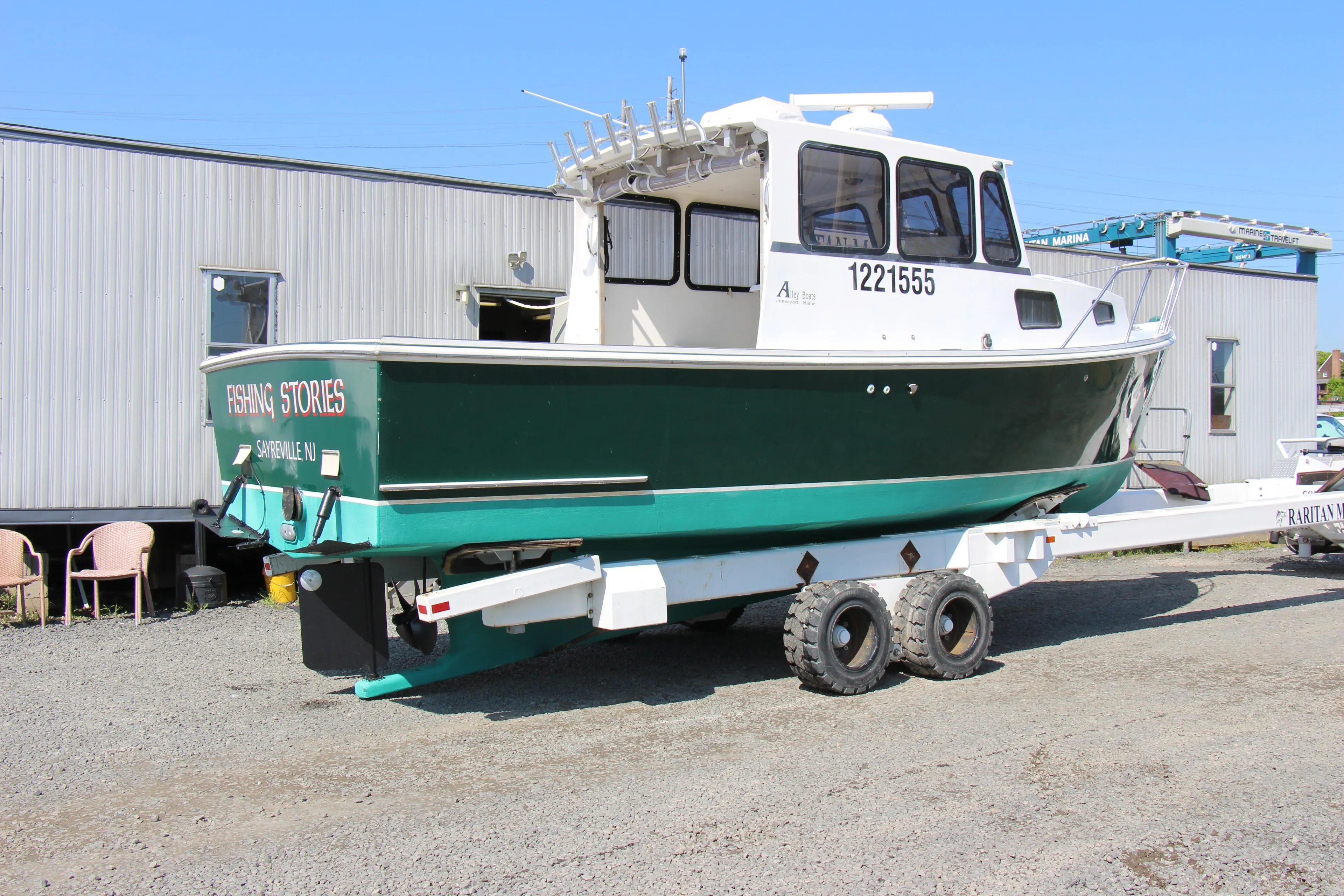 2009 Custom Alley Boats 28 Downeast on trailer, green hull, docked on gravel.