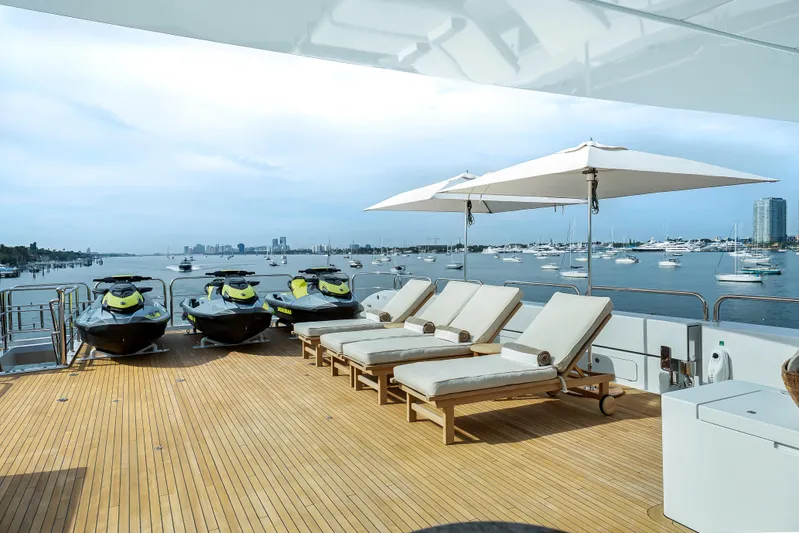 Silver Lining Yacht Photos Pics Luxurious 2016 Christensen Tri-Deck yacht deck with sun loungers and jet skis, overlooking marina.