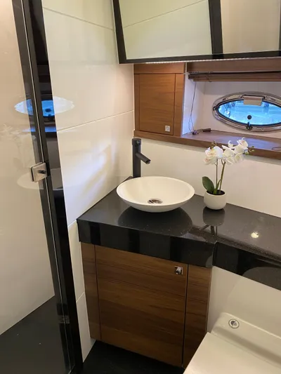  Yacht Photos Pics Luxurious yacht bathroom with modern sink, wooden cabinetry, and porthole window in Van der Heijden 2023.