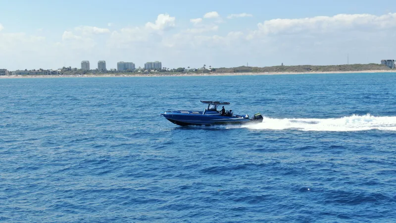 Riptide Yacht Photos Pics 2023 Statement 380 Open boat cruising on blue ocean near coastline.