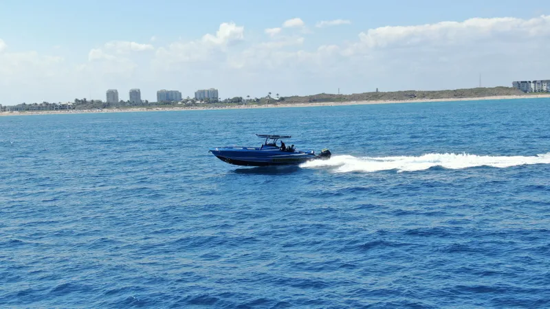 Riptide Yacht Photos Pics 2023 Statement 380 Open boat cruising on blue ocean near coastline.