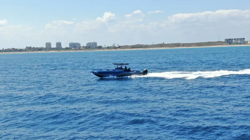 Riptide Yacht Photos Pics 2023 Statement 380 Open boat cruising on blue ocean near coastline.