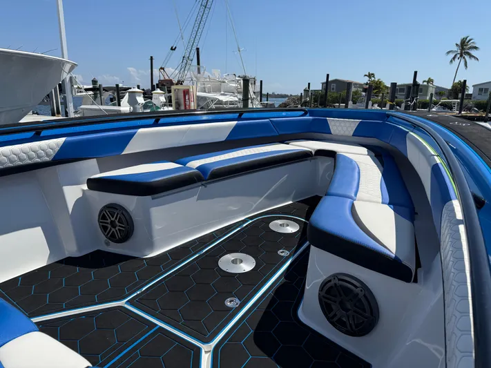 Riptide Yacht Photos Pics 2023 Statement 380 Open boat interior with blue and white seating, hexagonal flooring, and speakers.