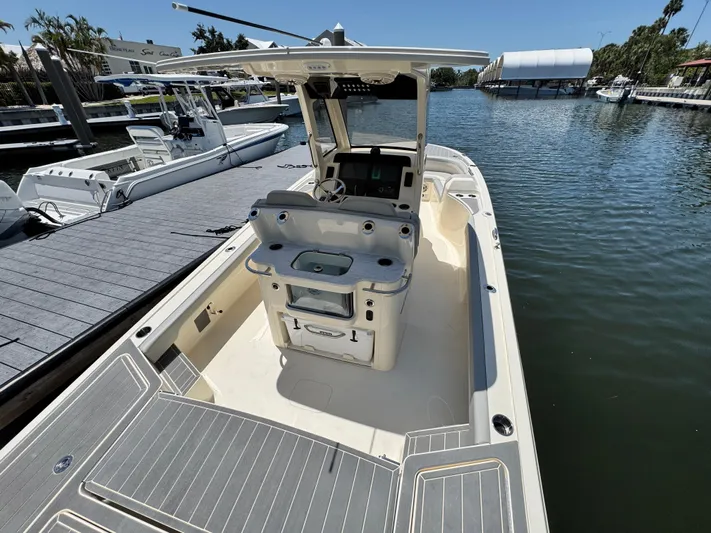  Yacht Photos Pics 2025 Scout 281 XSS boat docked on a sunny waterfront, showcasing spacious deck and seating.