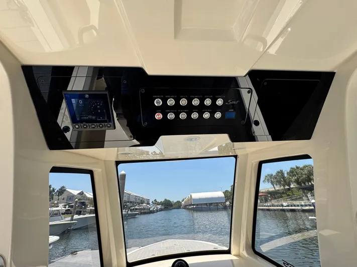  Yacht Photos Pics Interior view of 2025 Scout 281 XSS boat dashboard with control panel and waterway scenery.