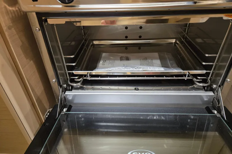 Mahalo Yacht Photos Pics Open oven inside a 2021 Beneteau Oceanis 30.1 yacht, showing a manual on the rack.