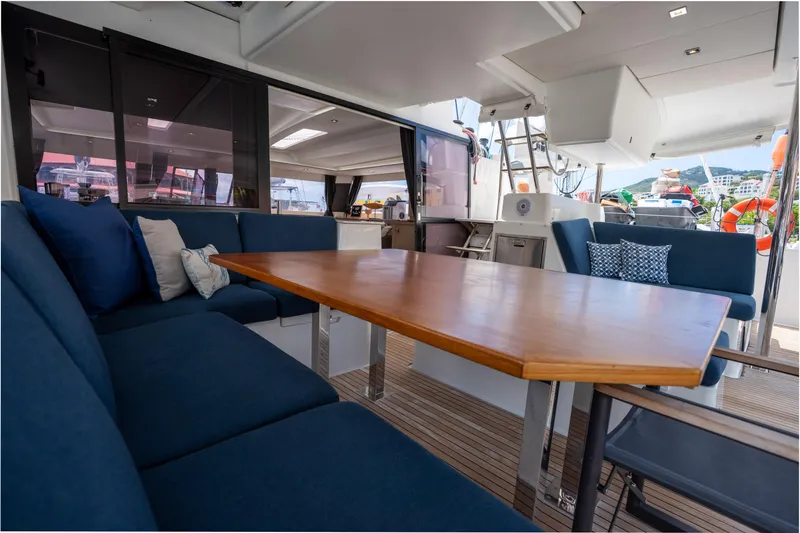  Yacht Photos Pics Spacious seating area on 2020 Fountaine Pajot SABA 50 yacht with wooden table and blue cushions.