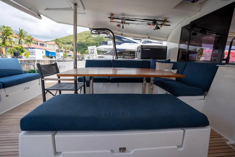  Yacht Photos Pics Spacious outdoor seating on 2020 Fountaine Pajot SABA 50 catamaran with blue cushions and wooden table.