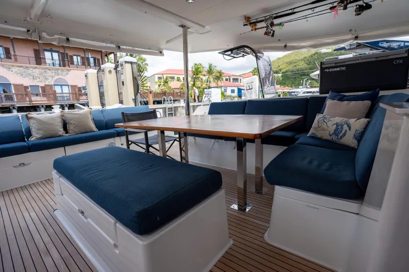  Yacht Photos Pics Spacious deck seating on 2020 Fountaine Pajot SABA 50 catamaran with wooden table and blue cushions.