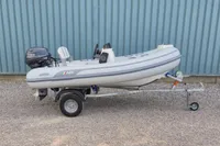 2024 AB Inflatables 10 ALX boat on trailer with Yamaha motor, parked on gravel.