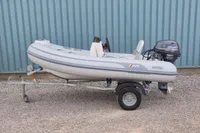 2024 AB Inflatables 10 ALX boat on trailer with Yamaha motor, parked on gravel.
