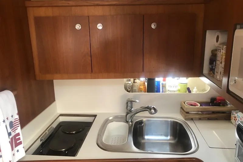  Yacht Photos Pics Compact yacht kitchen with wooden cabinets, sink, and stove in a 1998 Tiara Yachts 3700 Open.