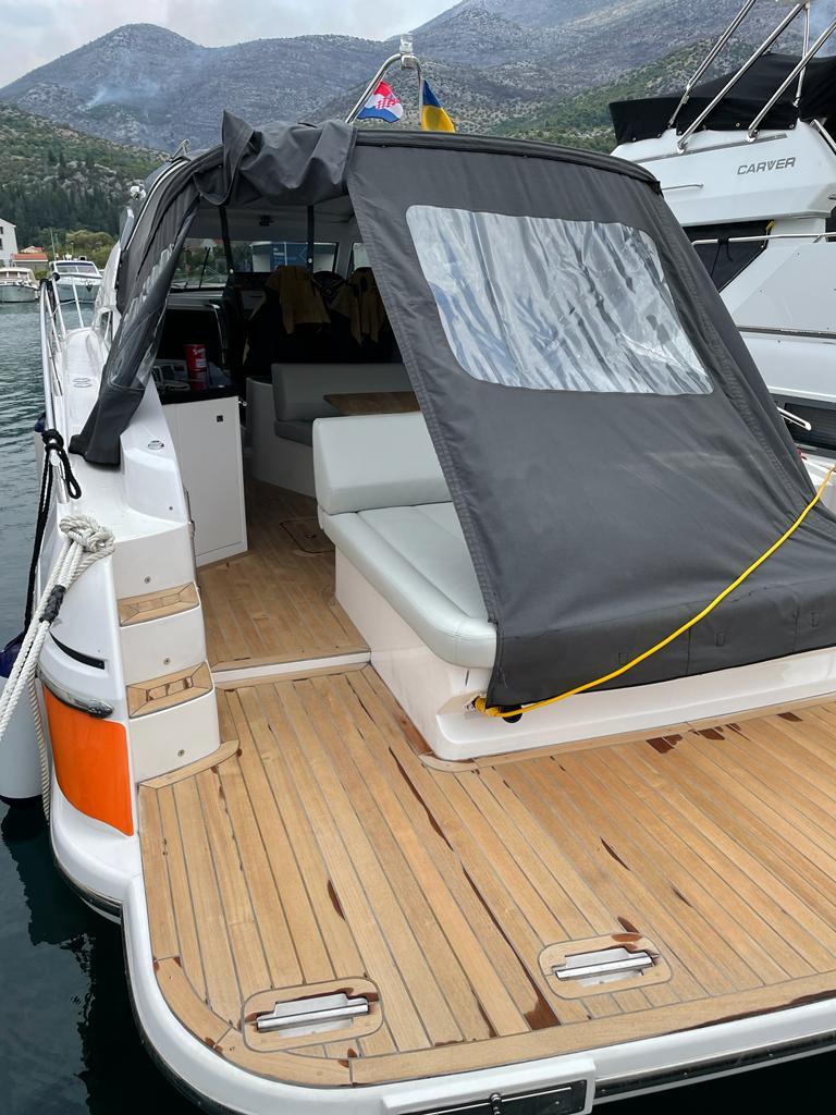 2021 Focus Power 36 yacht with teak deck and covered seating area in marina.