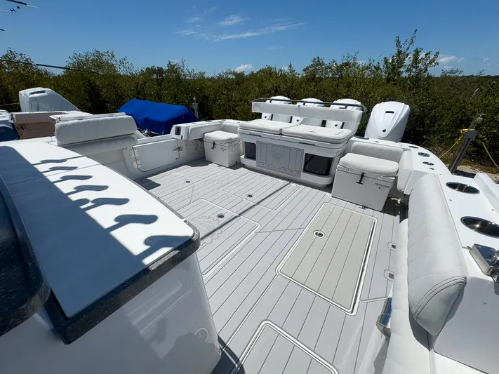  Yacht Photos Pics 2019 HCB 53 Sueños boat deck with seating, storage, and engines, under clear blue sky.