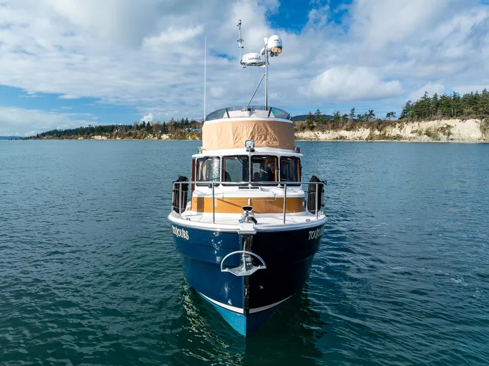 Toujours Yacht Photos Pics 2021 Ranger Tugs R-31 CB boat on calm water with scenic shoreline background.