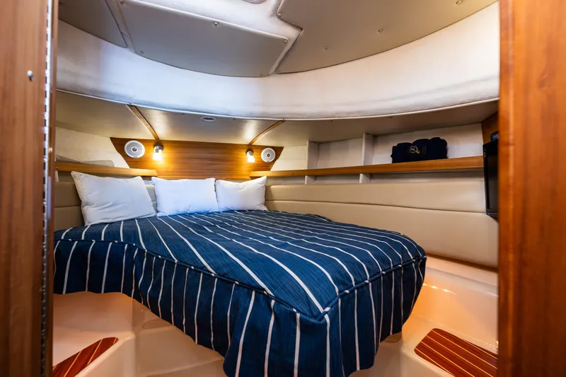 Toujours Yacht Photos Pics Cozy cabin interior of 2021 Ranger Tugs R-31 CB with striped bedding and ambient lighting.