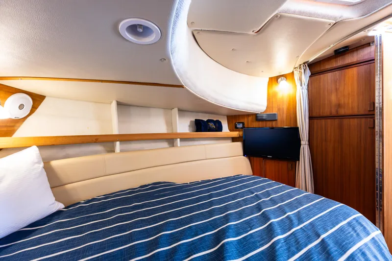 Toujours Yacht Photos Pics 2021 Ranger Tugs R-31 CB cabin interior with striped bedding and wooden accents.