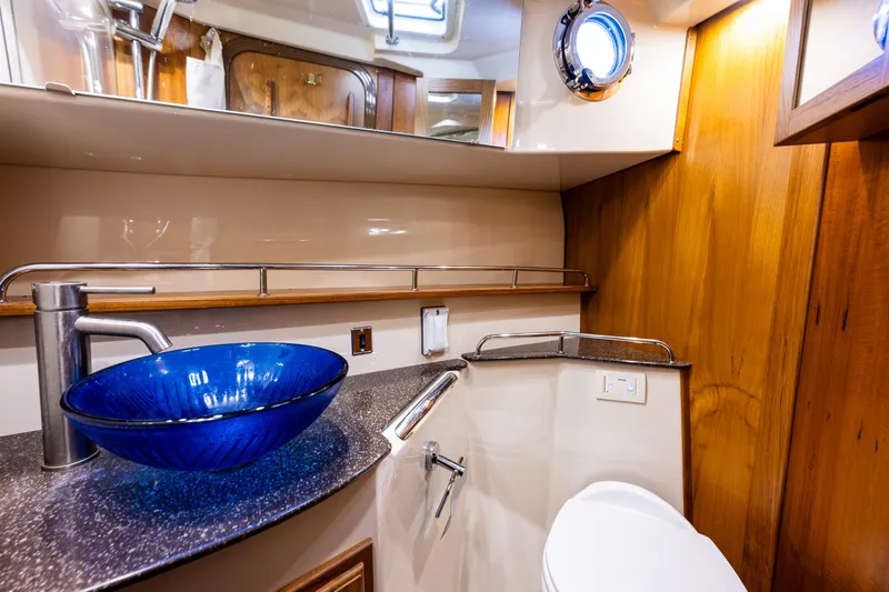 Toujours Yacht Photos Pics Luxurious 2021 Ranger Tugs R-31 CB bathroom with blue glass sink and wooden accents.