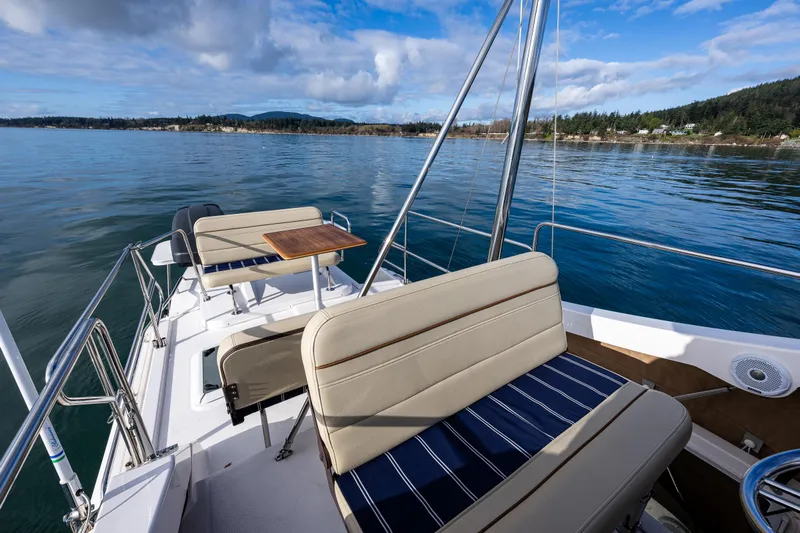 Toujours Yacht Photos Pics 2021 Ranger Tugs R-31 CB boat deck with seating, overlooking calm waters and scenic shoreline.