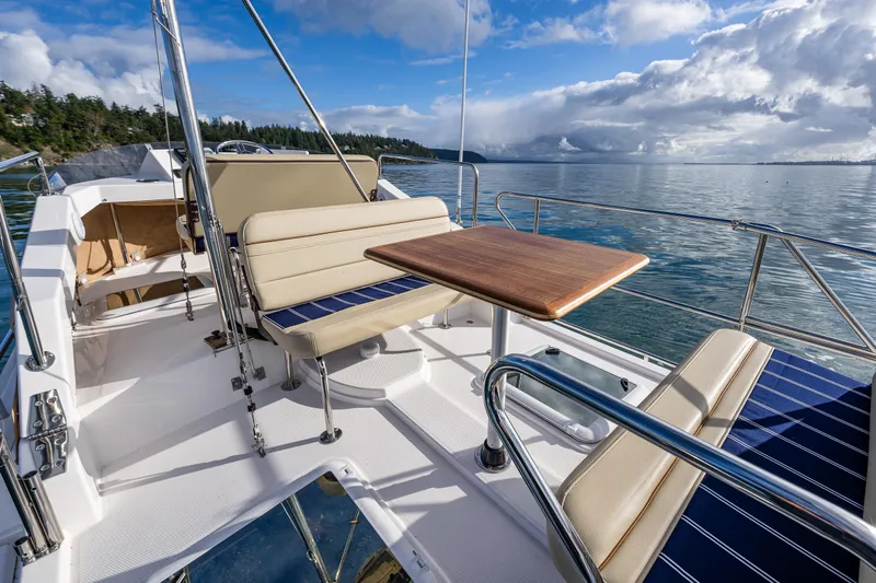 Toujours Yacht Photos Pics 2021 Ranger Tugs R-31 CB boat deck with seating and table, scenic water view.