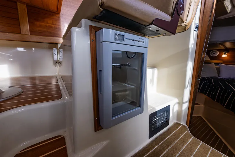 Toujours Yacht Photos Pics 2021 Ranger Tugs R-31 CB interior with compact fridge and wooden accents.