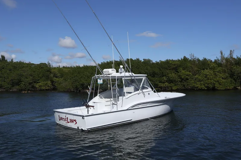 Lures & Liars Yacht Photos Pics 2002 Miller Marine 36 Express boat on calm water, surrounded by lush greenery.