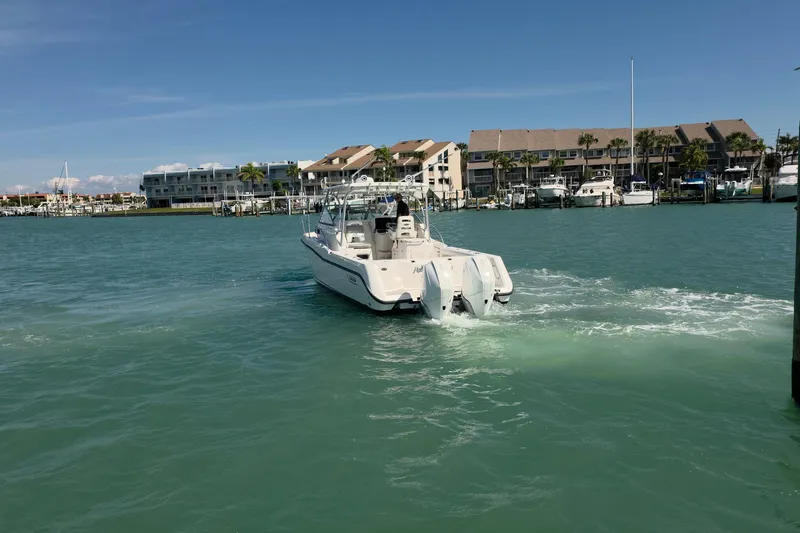  Yacht Photos Pics 2007 Boston Whaler 305 Conquest boat cruising in a marina with waterfront buildings.