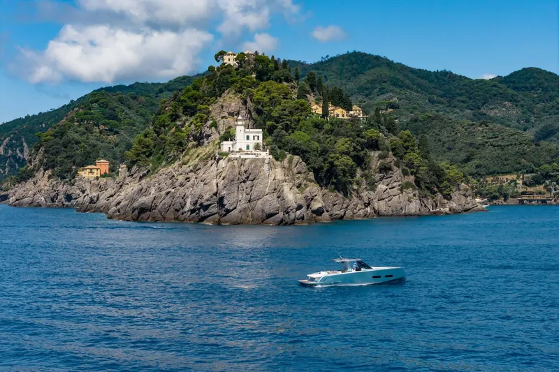  Yacht Photos Pics 2026 Pardo Yachts P43 cruising near scenic rocky coastline with lush greenery.