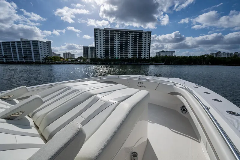  Yacht Photos Pics 2023 Prowler Renaissance 36 boat with luxurious seating, cityscape in background, under a partly cloudy sky.