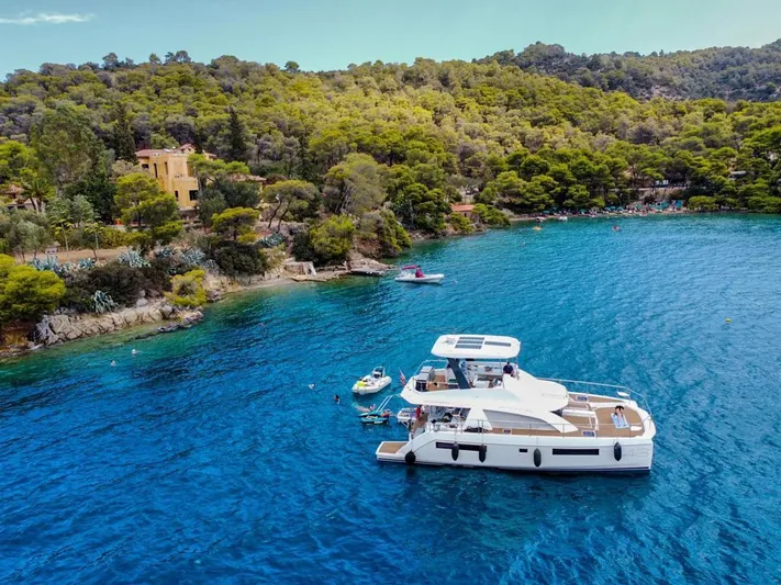  Yacht Photos Pics 2020 Leopard 43 Powercat yacht anchored in a scenic, forested coastal bay.