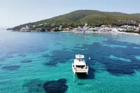 2020 Leopard 43 Powercat anchored in clear turquoise waters near a coastal village.