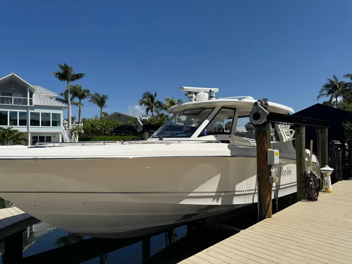  Yacht Photos Pics 2018 Boston Whaler 350 Realm docked near waterfront home, clear blue sky.