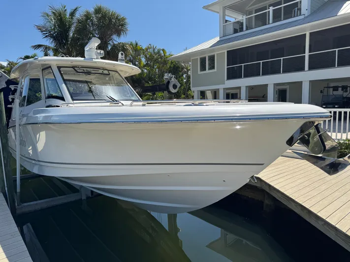  Yacht Photos Pics 2018 Boston Whaler 350 Realm boat docked near a modern house.