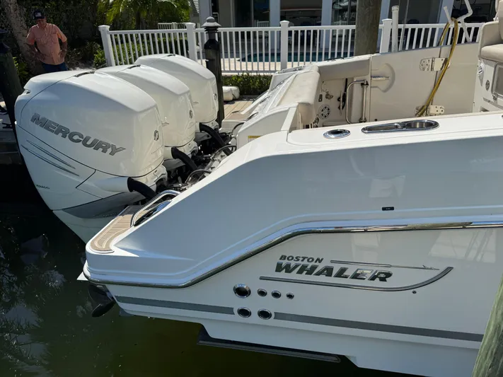  Yacht Photos Pics 2018 Boston Whaler 350 Realm with Mercury outboard engines docked by a white fence.