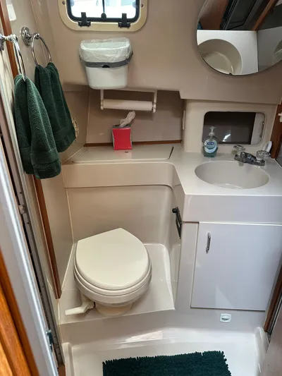 River Miss Yacht Photos Pics 1997 Mainship 350 boat bathroom with toilet, sink, mirror, and green towels.