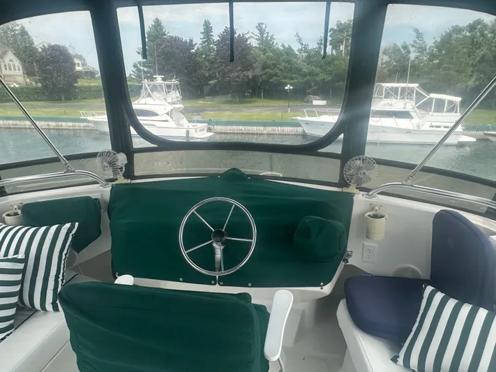 River Miss Yacht Photos Pics 1997 Mainship 350 boat interior with green seating, steering wheel, and marina view.