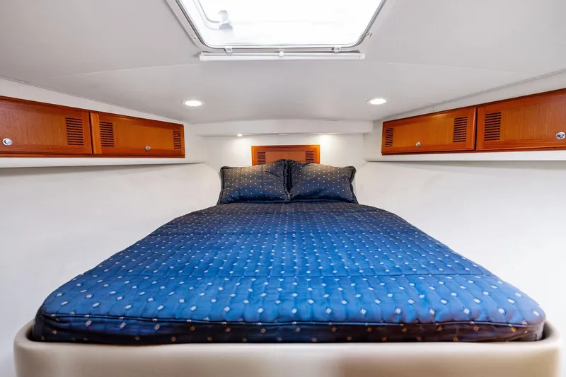 Pescador Yacht Photos Pics 2004 Cabo 40 Hardtop Express cabin with blue bedding and wooden storage cabinets.