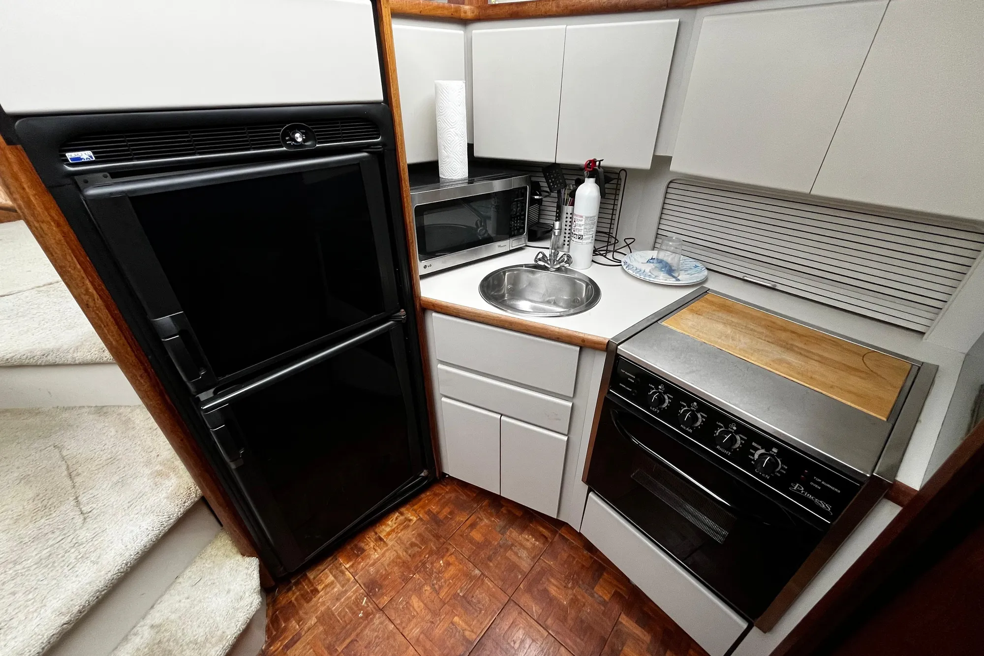 Compact kitchen in 1991 Carver 33 Aft Cabin Motor Yacht with appliances and wood accents.