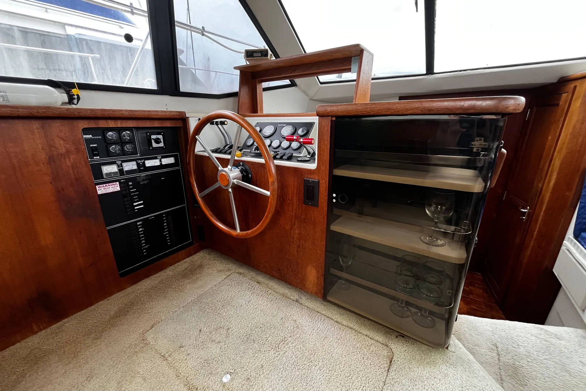 1991 Carver 33 Aft Cabin Motor Yacht helm with wooden steering wheel and glass cabinet.