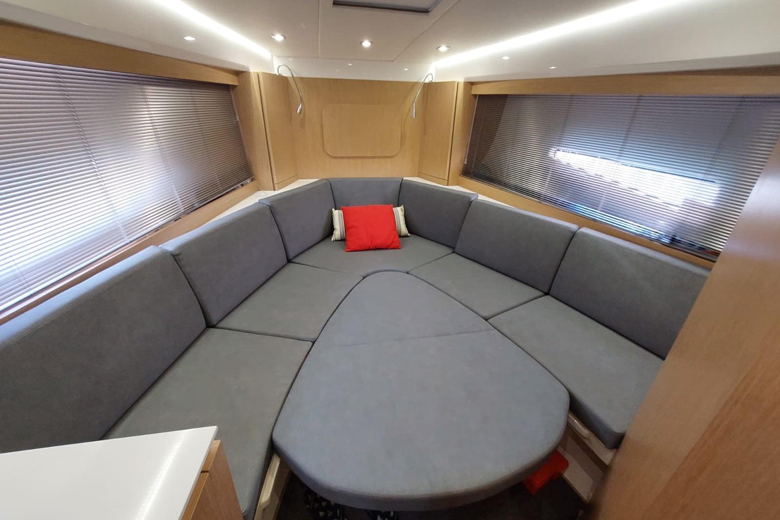 Luxurious interior of 2017 Need Yacht 32 with spacious gray seating and red accent pillow.