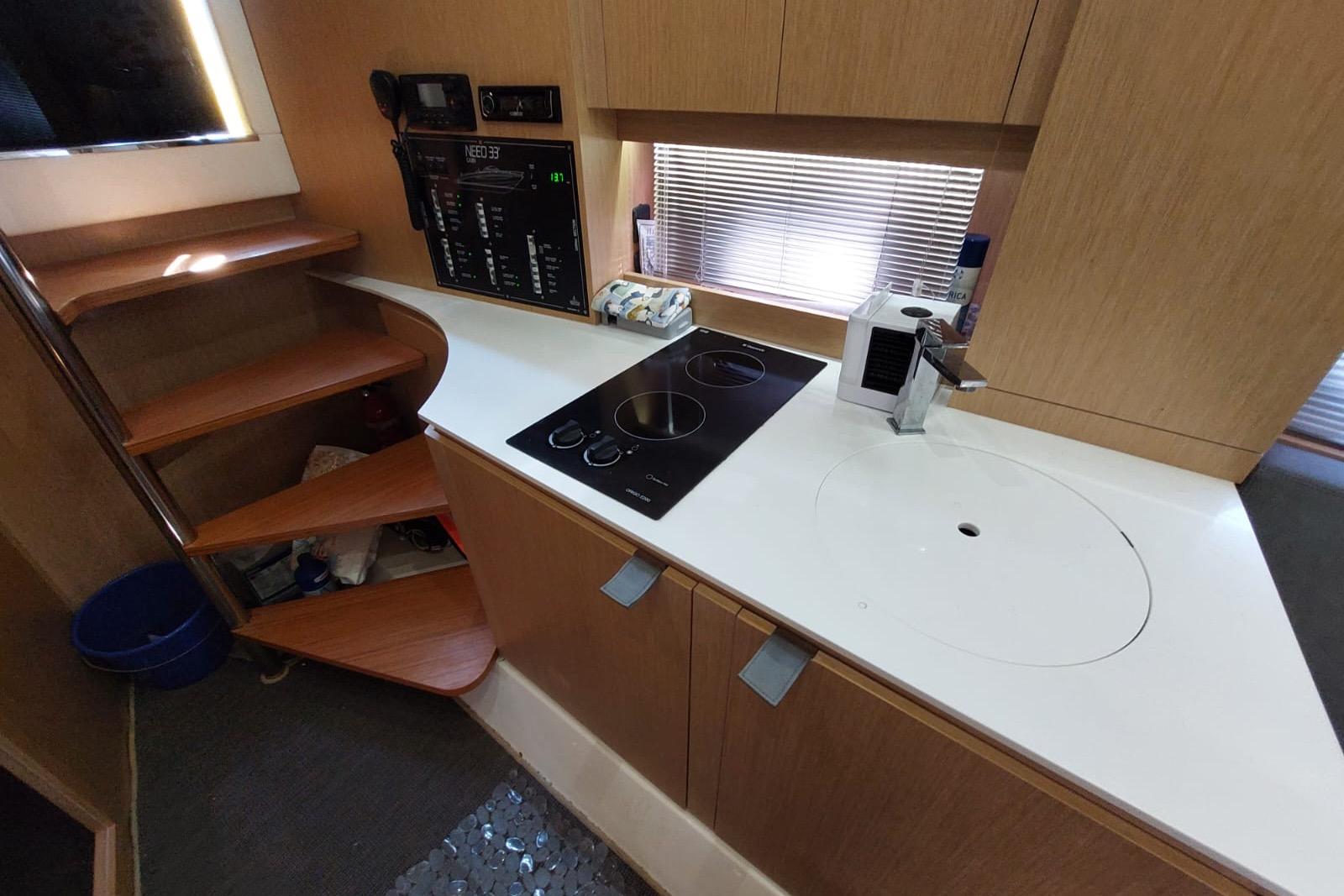 Compact kitchen area in a 2017 Need Yacht 32, featuring a stove and modern cabinetry.