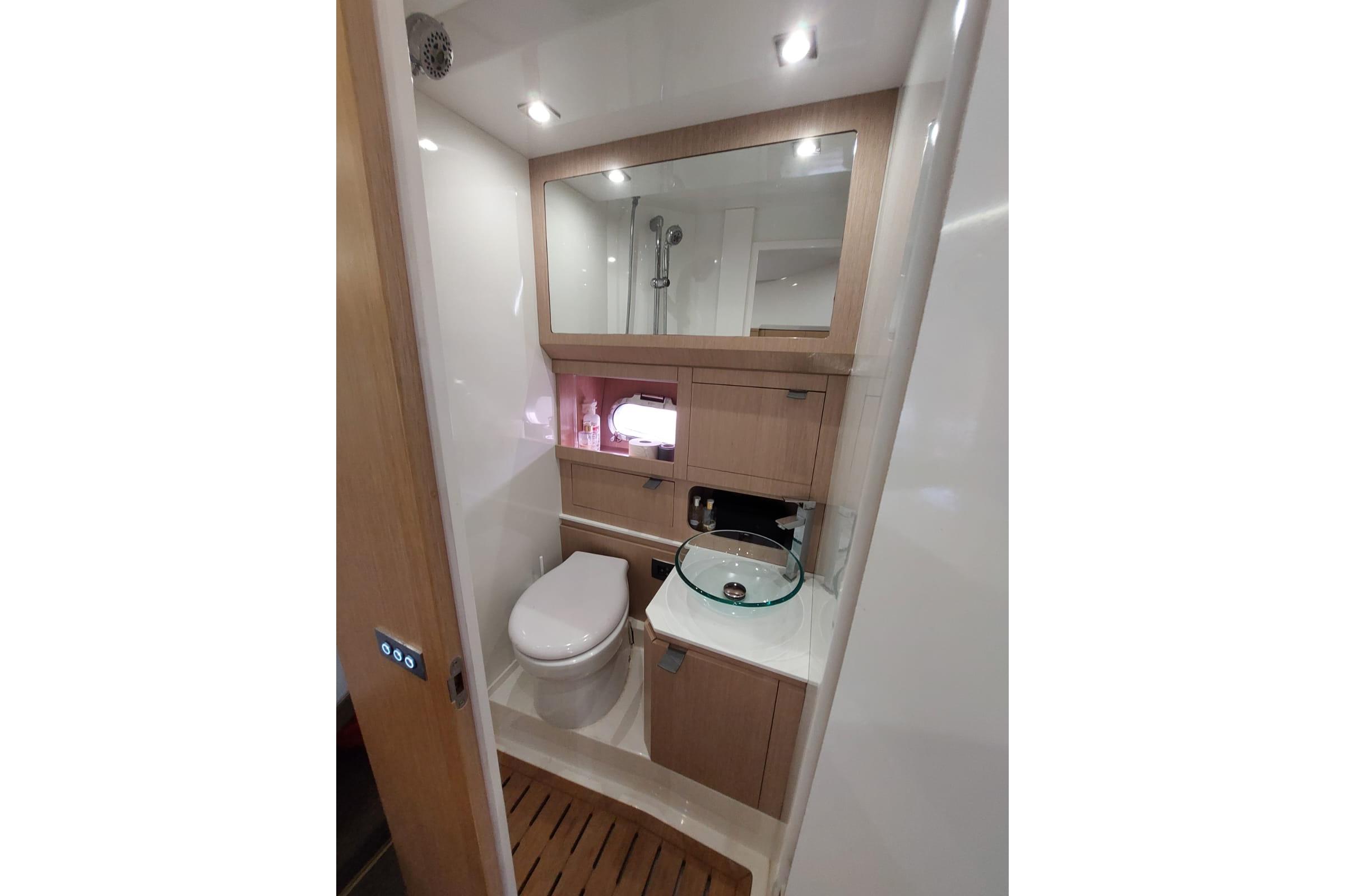 Modern yacht bathroom with toilet, glass sink, and wooden cabinetry in Need Yacht 32, 2017 model.