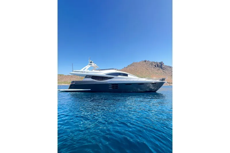  Yacht Photos Pics Luxurious 2010 Numarine 78 yacht on clear blue water with scenic rocky backdrop.