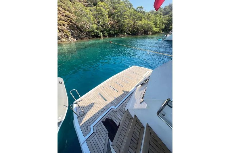  Yacht Photos Pics Luxury Numarine 78 yacht docked in serene, clear blue waters, surrounded by lush greenery.